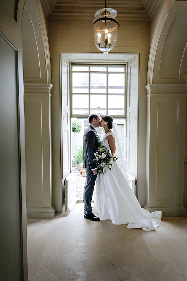 bride and groom kiss in hall of Shilstone House