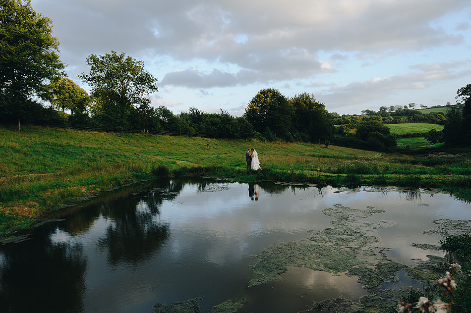 bride and groom reflected in the ponds at Shilstone House wedding venue